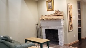 Ein Wohnzimmer mit Kamin, einer Couch, einem Tisch und einem Teppich.