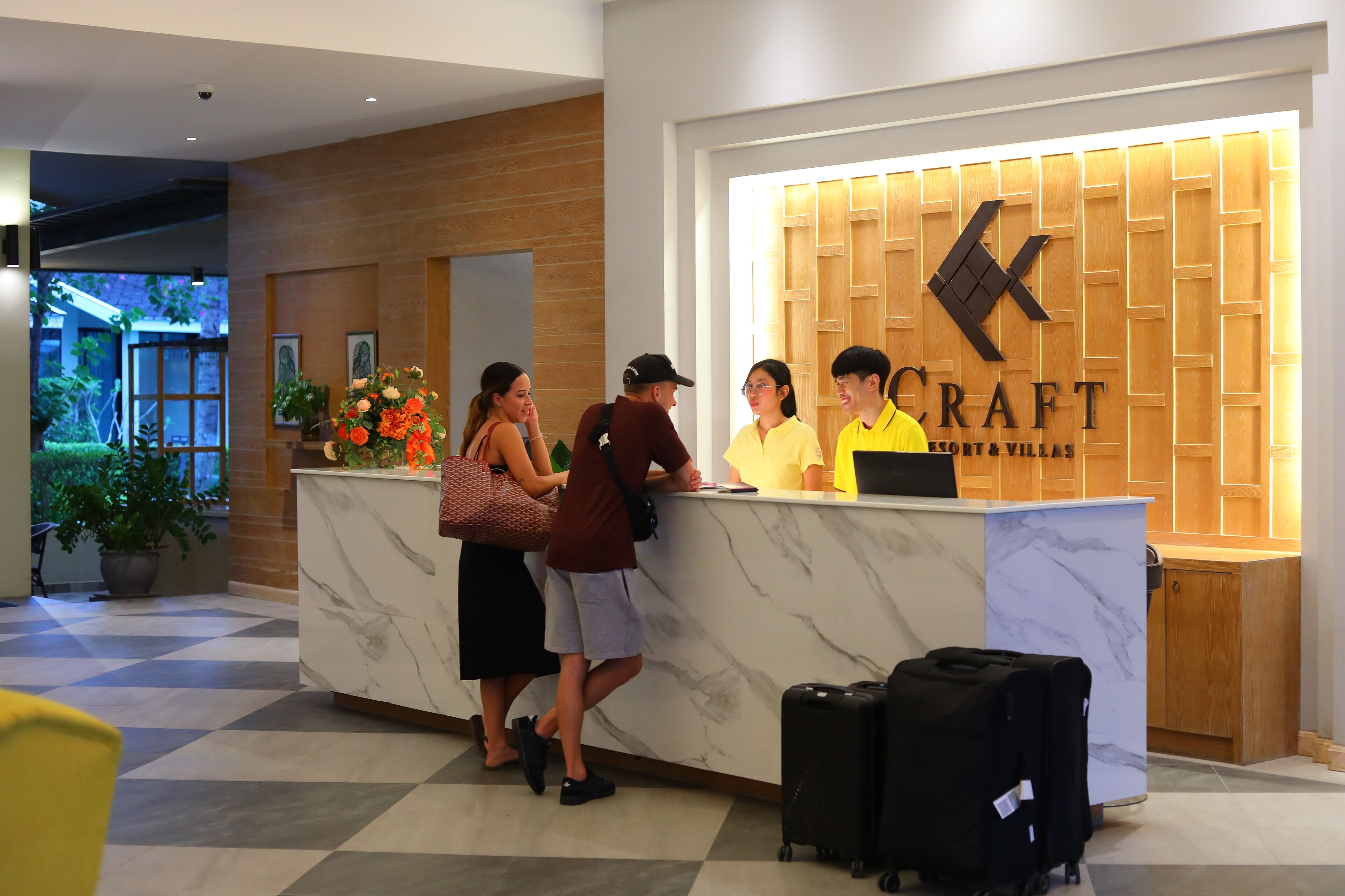 Una recepción con un panel de madera y la palabra "CRAFT" en la pared, una planta en maceta y un mostrador de registro.