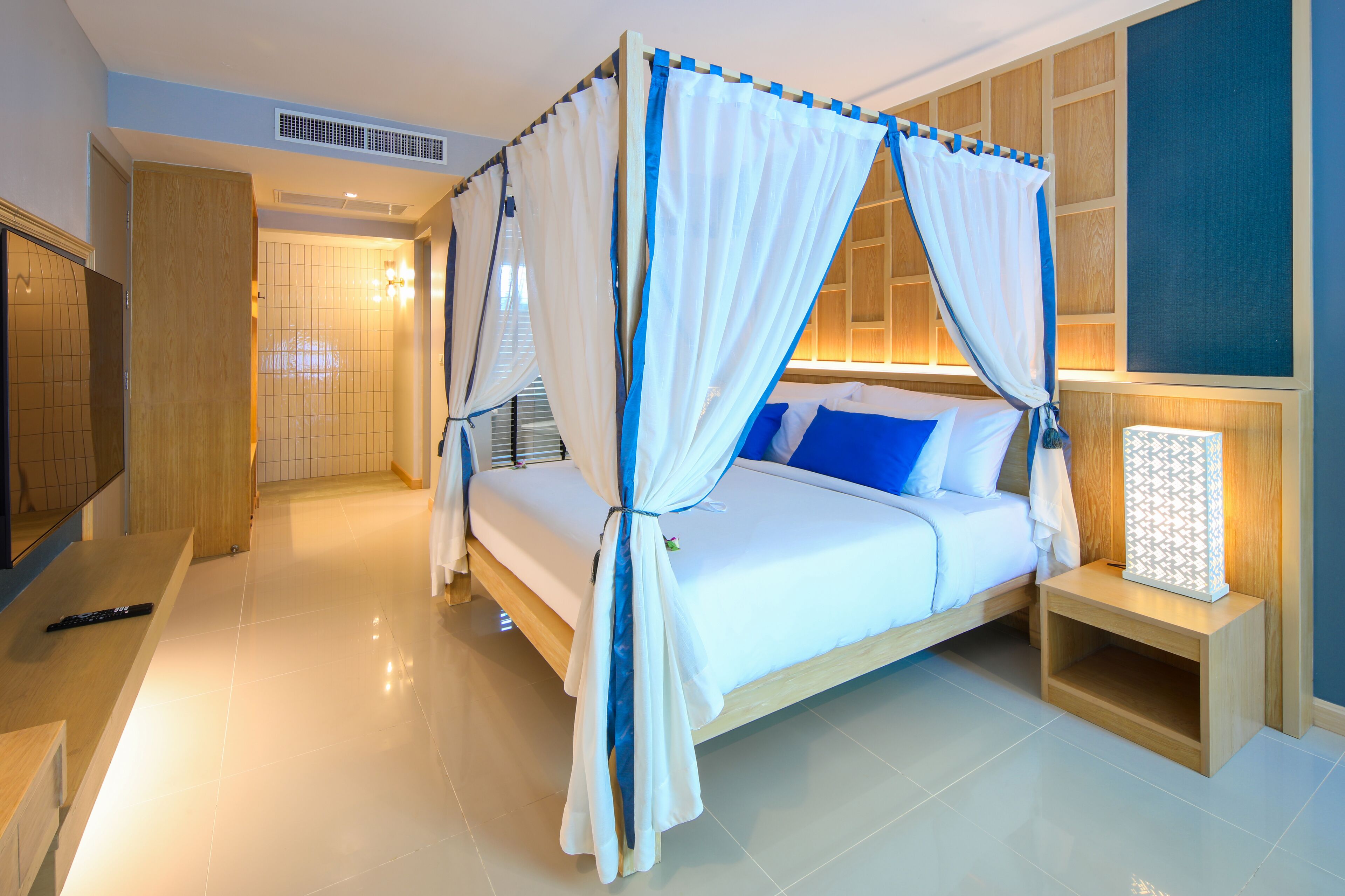 A bedroom with a four-poster bed, a bedside table, and a TV.