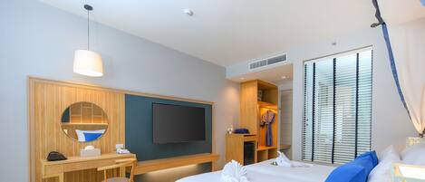 A hotel room with a bed, a desk, a chair, a TV, and a window with blinds.