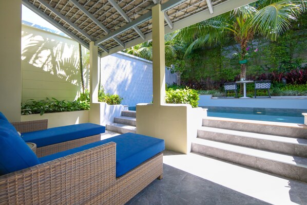 A covered outdoor area with wicker furniture, a pool, and steps leading to a patio. - CRAFT Resort & Villas (Ratsada)