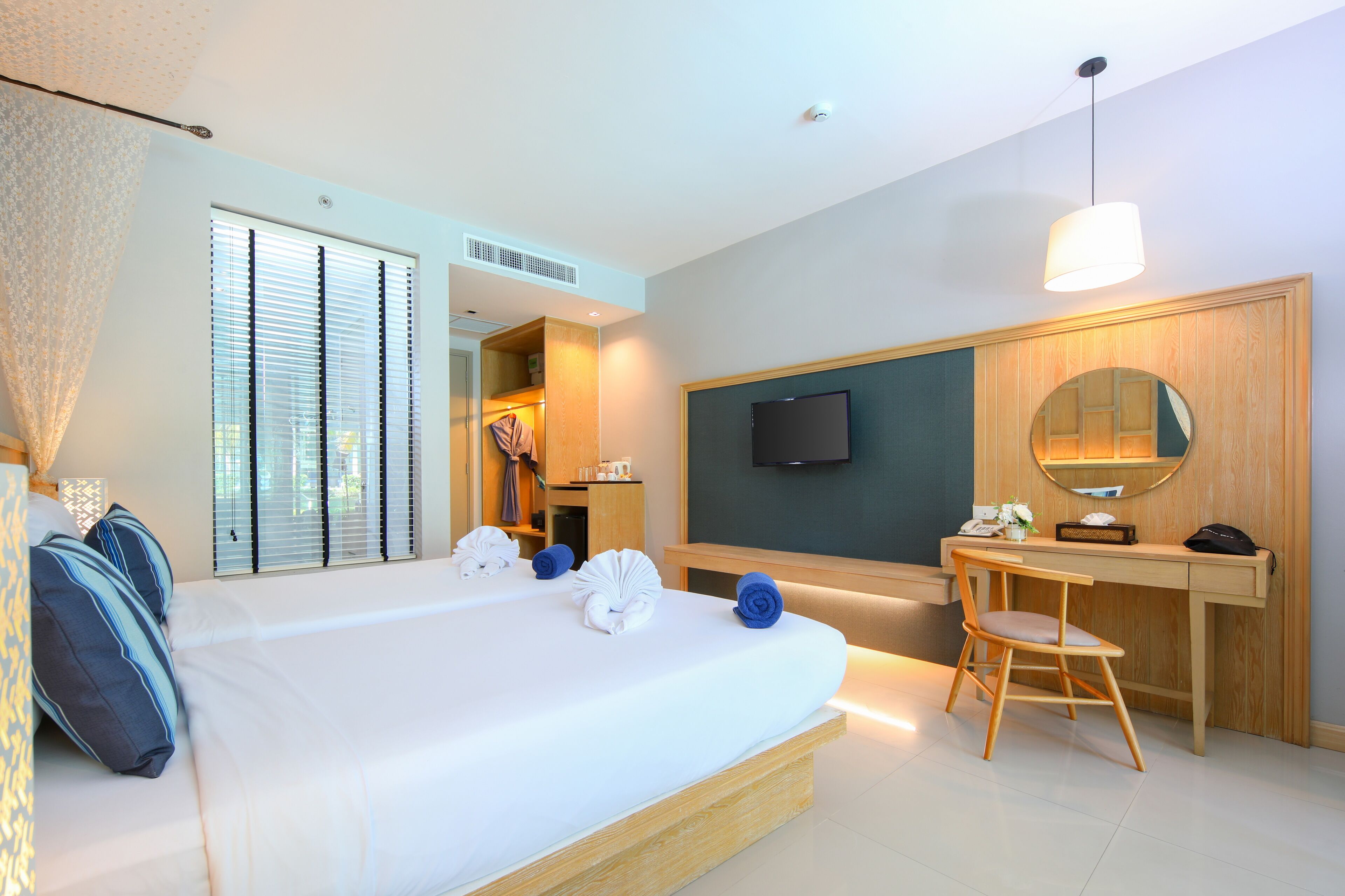 Una habitación de hotel con una cama, un escritorio, una silla, un televisor y un espejo.