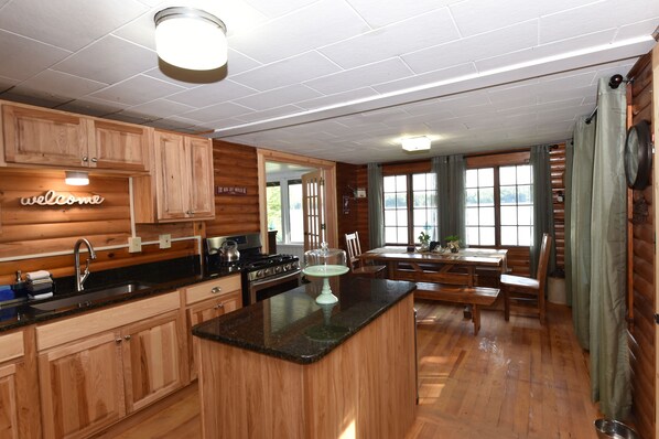 A wooden cabin-style kitchen with a central island, wooden cabinets, and a 'welcome' sign.