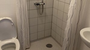 A small, tiled bathroom with a shower, toilet, and sink.