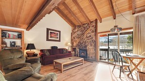 A cozy living room with a fireplace, wooden furniture, and a stone accent wall. - Snowcreek 91: Nice, Dog Friendly, Close to Red Lin (Mammoth Lakes)