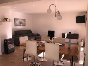 A modern dining area with a wooden table, white chairs, and a black sofa.