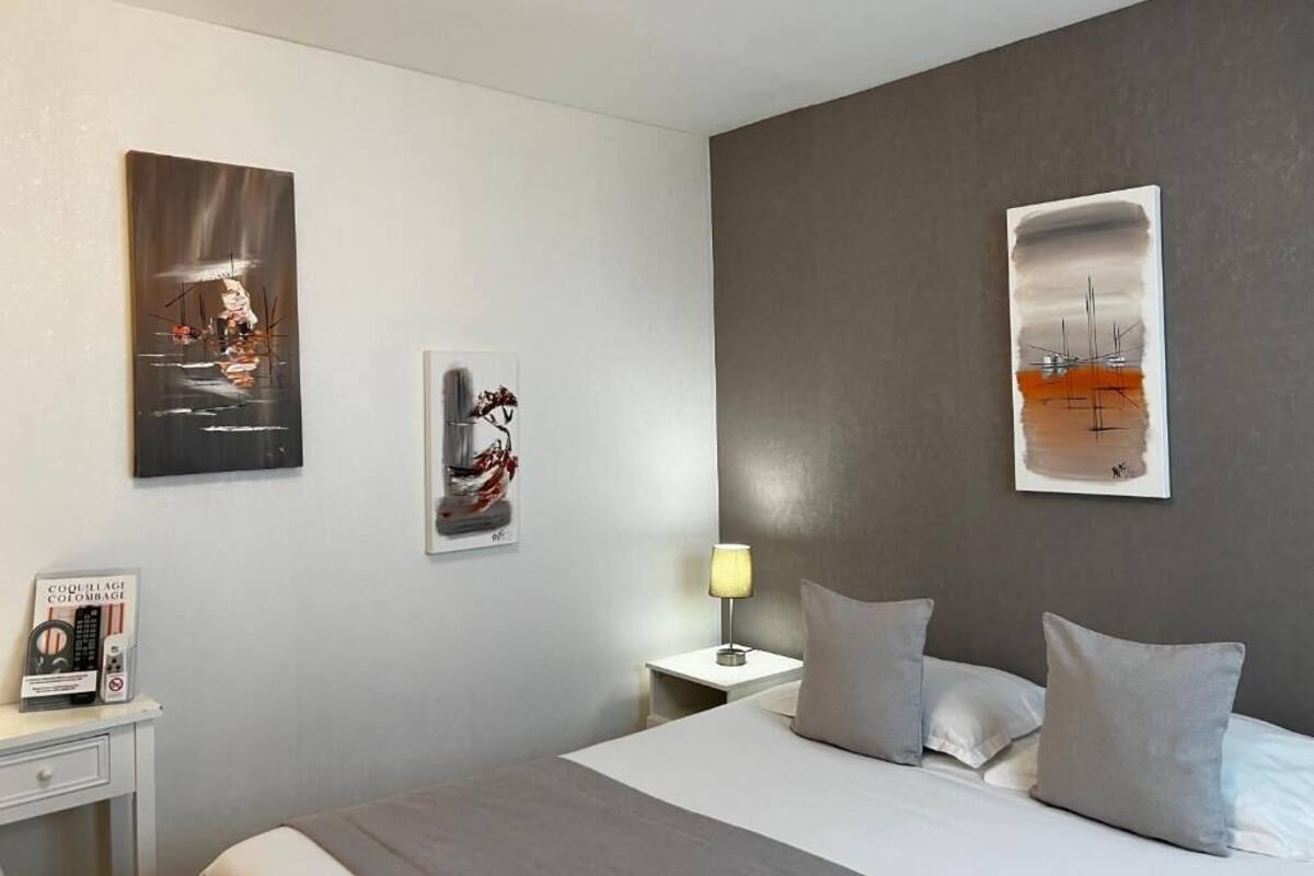 A hotel room with a bed, bedside tables, and artwork on the walls.