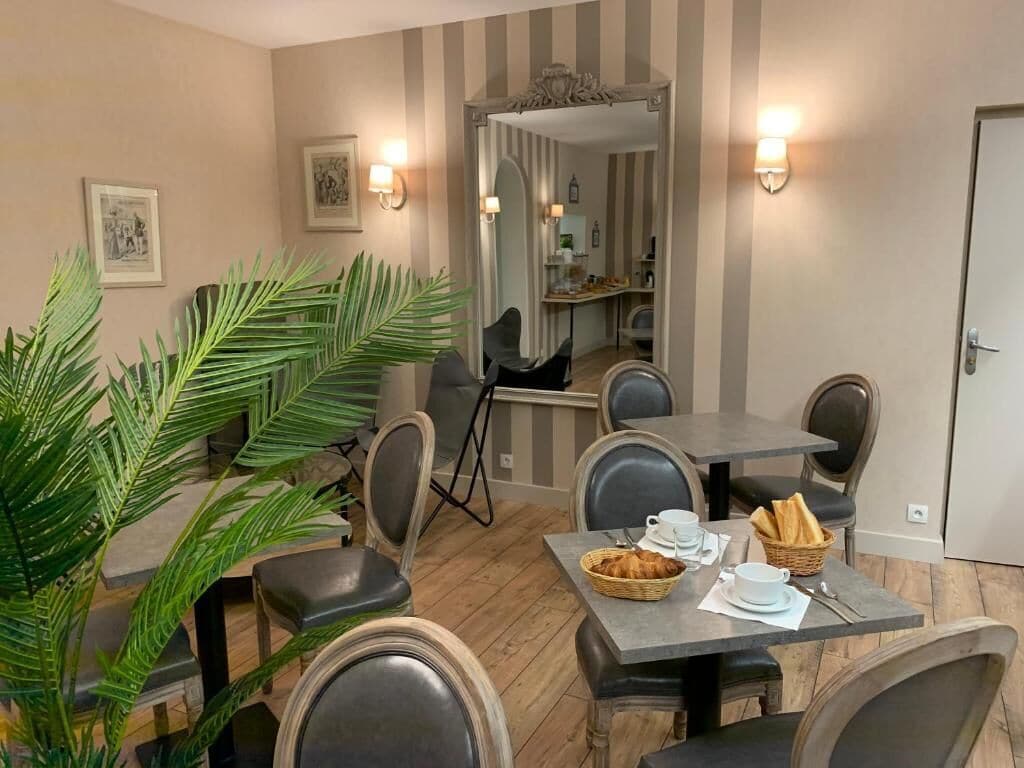Een eetgedeelte met een tafel voor twee personen, stoelen, een plant en een spiegel.