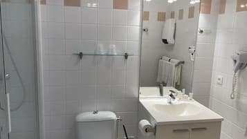 A bathroom with a glass shower enclosure, a toilet, a sink with a mirror, and a towel rack.