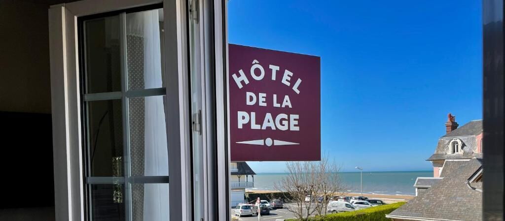 Letrero de hotel que dice "Hôtel de la Plage", con vista a la playa y al océano.