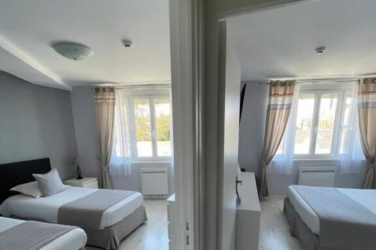 A hotel room with two beds, a desk, and a window with curtains.