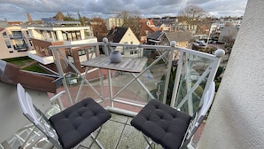 Ein Balkon mit zwei gepolsterten Stühlen, einem kleinen Tisch und Blick auf die umliegende Gegend.