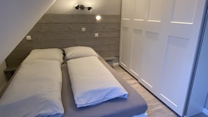 Ein kleines, modernes Schlafzimmer mit Schlafplatz in der Art eines Lofts, integriertem Kleiderschrank und Einbauleuchten.