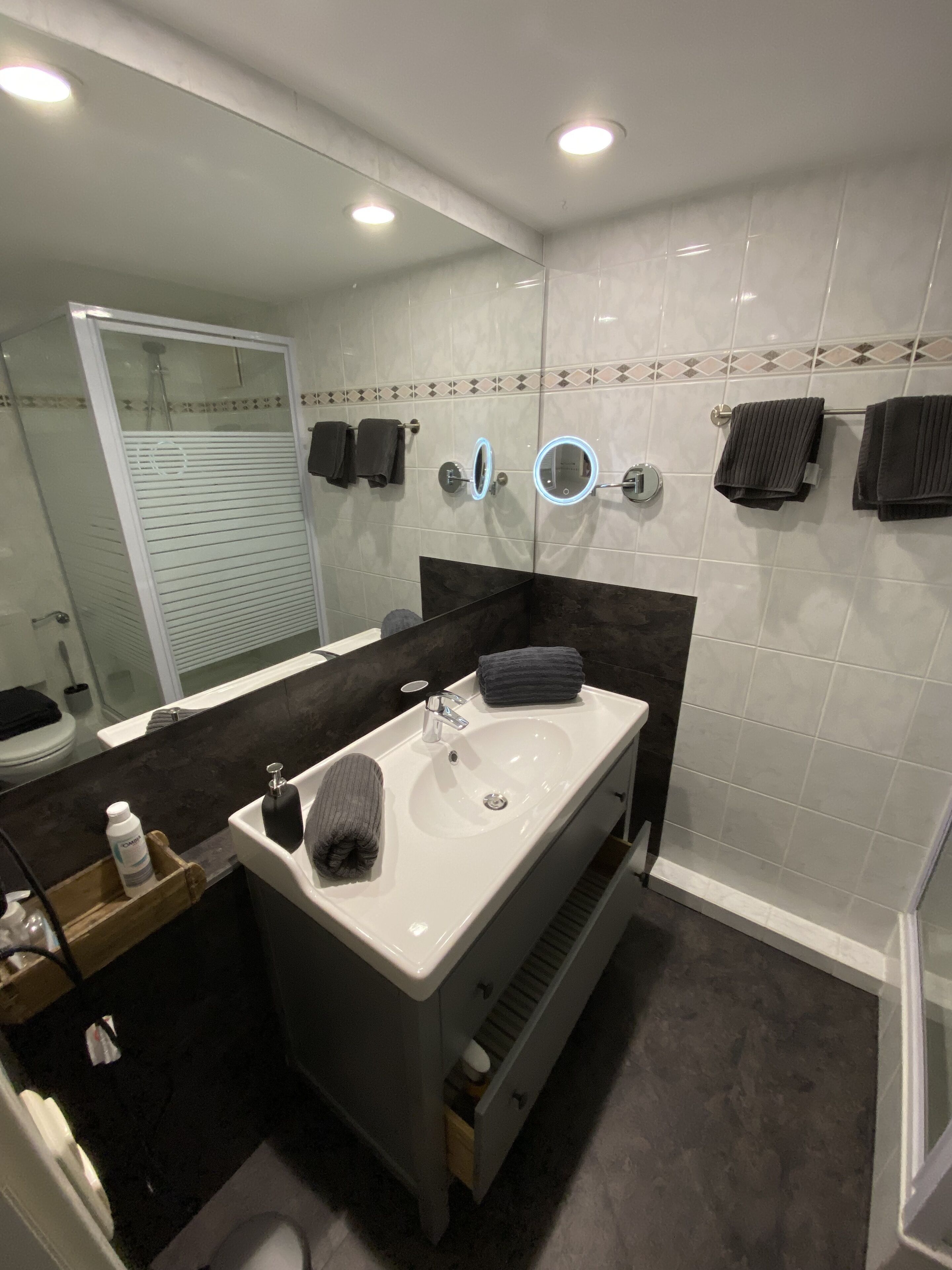 A modern bathroom with a large mirror, a sink, and a shower area.