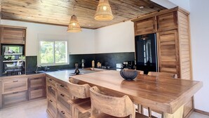 Une cuisine moderne avec des meubles en bois, un grand îlot central doté de tabourets et un éclairage suspendu.