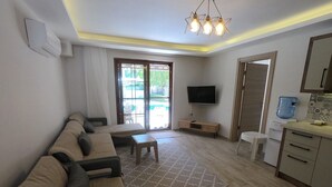 A living room with a sofa, a coffee table, a TV, and a kitchen area with a water dispenser. - NEW LISTING! BEAUTIFUL 4 BEDROOM ALL EN-SUITE VILLA IN GULPINAR AREA OF DALYAN!! (Dalyan)