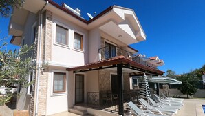A two-story building with a covered patio area featuring lounge chairs and a table. - NEW LISTING! BEAUTIFUL 4 BEDROOM ALL EN-SUITE VILLA IN GULPINAR AREA OF DALYAN!! (Dalyan)