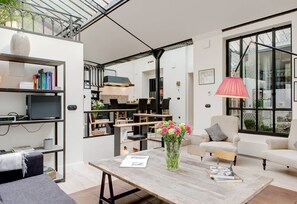Un salon moderne avec une table basse en bois, un canapé, une bibliothèque et un coin repas.
