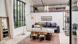 Un salón moderno con un gran ventanal, un sofá, una mesa de centro y un balcón con barandilla.