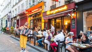 Una escena callejera con mesas y sillas en la terraza de un restaurante.