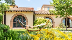 A building with arched windows and a hammock in the garden.