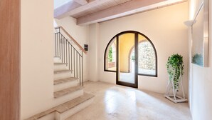 Una escalera conduce a una puerta con un arco de piedra, una planta en maceta y una lámpara moderna.