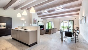 A modern kitchen with a central island, a dining area with a table and chairs, and a living area with a sofa.