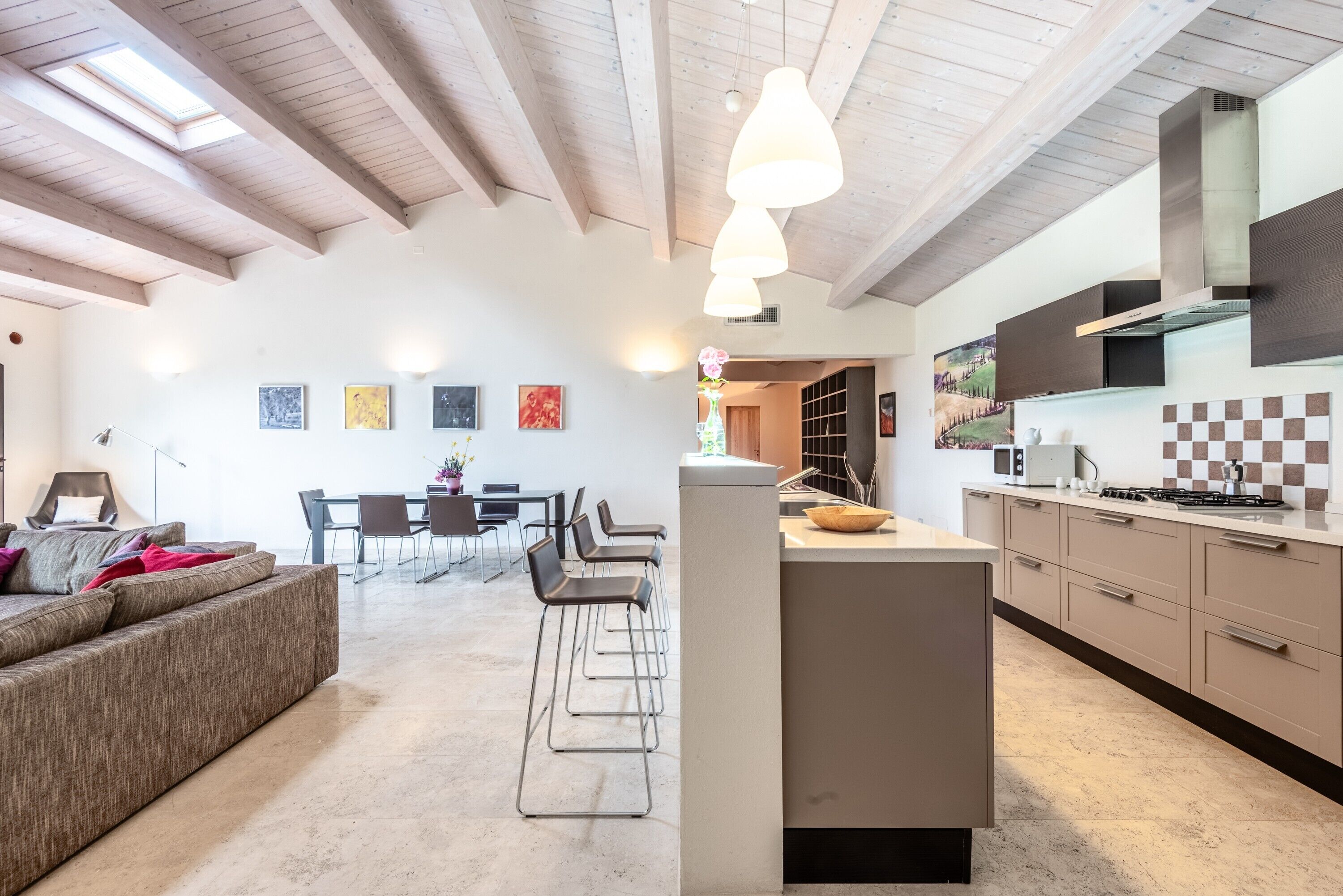 A modern kitchen with a central island, a dining area with chairs, and a sofa.