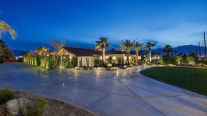 A residential property with a curved driveway, palm trees, and a well-maintained lawn. - SDR Hideaway! Misters, Saltwater Pool/Spa, Putt Putt! (Thousand Palms)