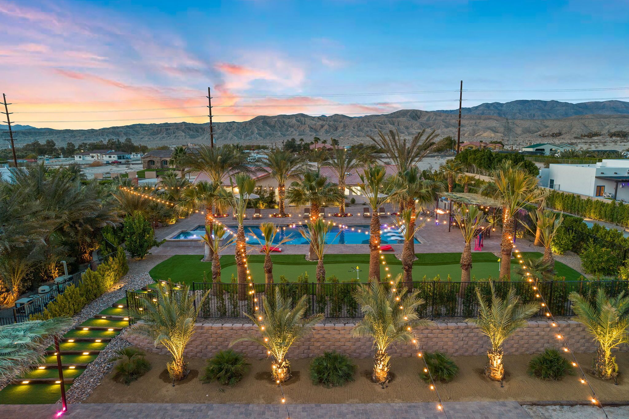 A resort with a swimming pool, palm trees, and a view of mountains.