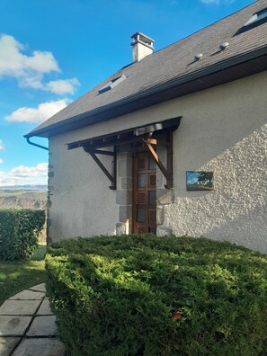A house with a stone exterior, a wooden door, and a small picture on the wall.