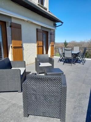 An outdoor patio with wicker furniture, a table, and chairs.