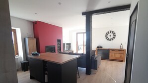 Une cuisine moderne avec un îlot central en bois, un mur d’accent rouge et une grande horloge au mur.