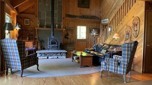 Ein gemütliches Blockhaus mit Kamin, Karo-Möbeln und Holzwänden.