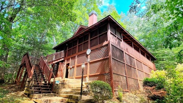 A traditional wooden structure with a staircase leading to a porch, surrounded by lush greenery. - Gem in the Glades, secluded, minutes from Gatlinbu (Gatlinburg)