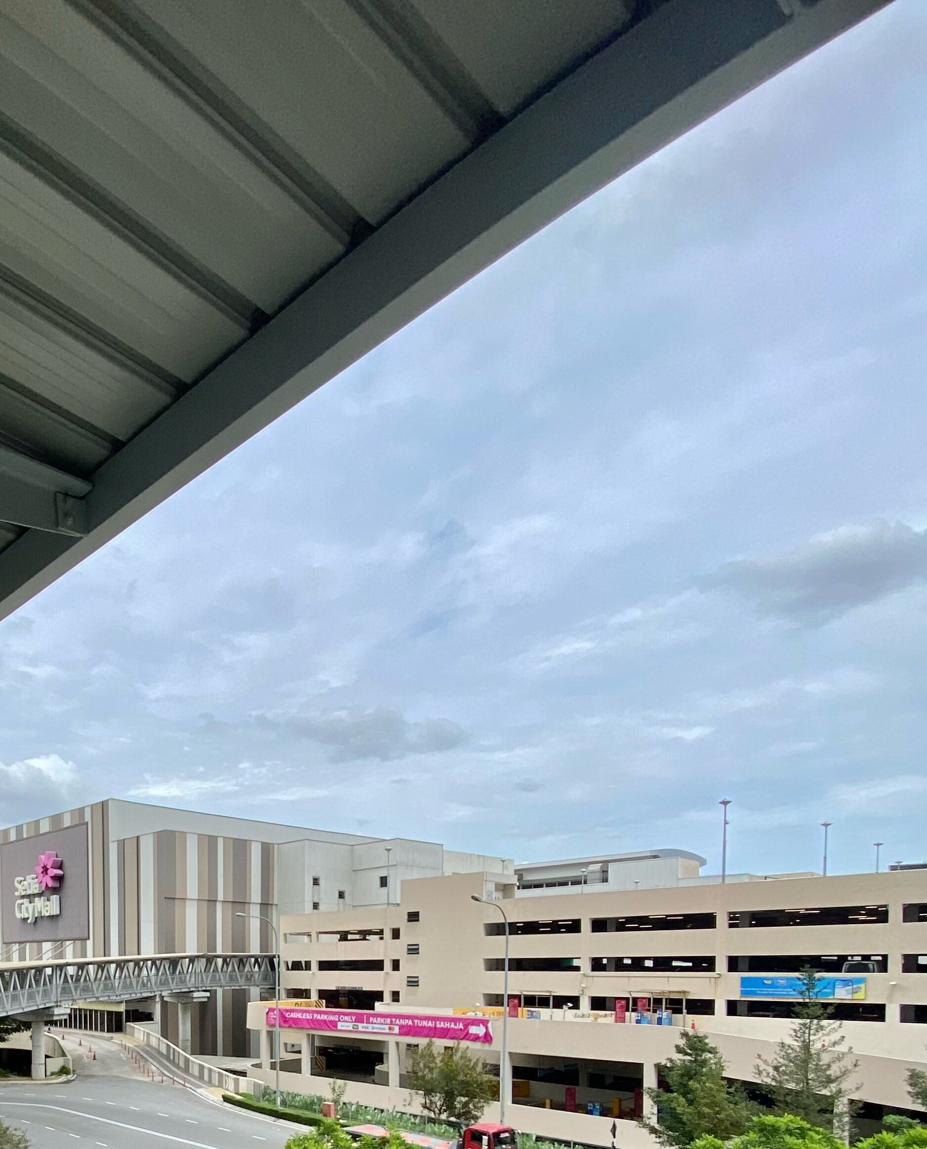 A multi-story parking garage with a pedestrian bridge leading to a building with a sign that reads "City Mall."