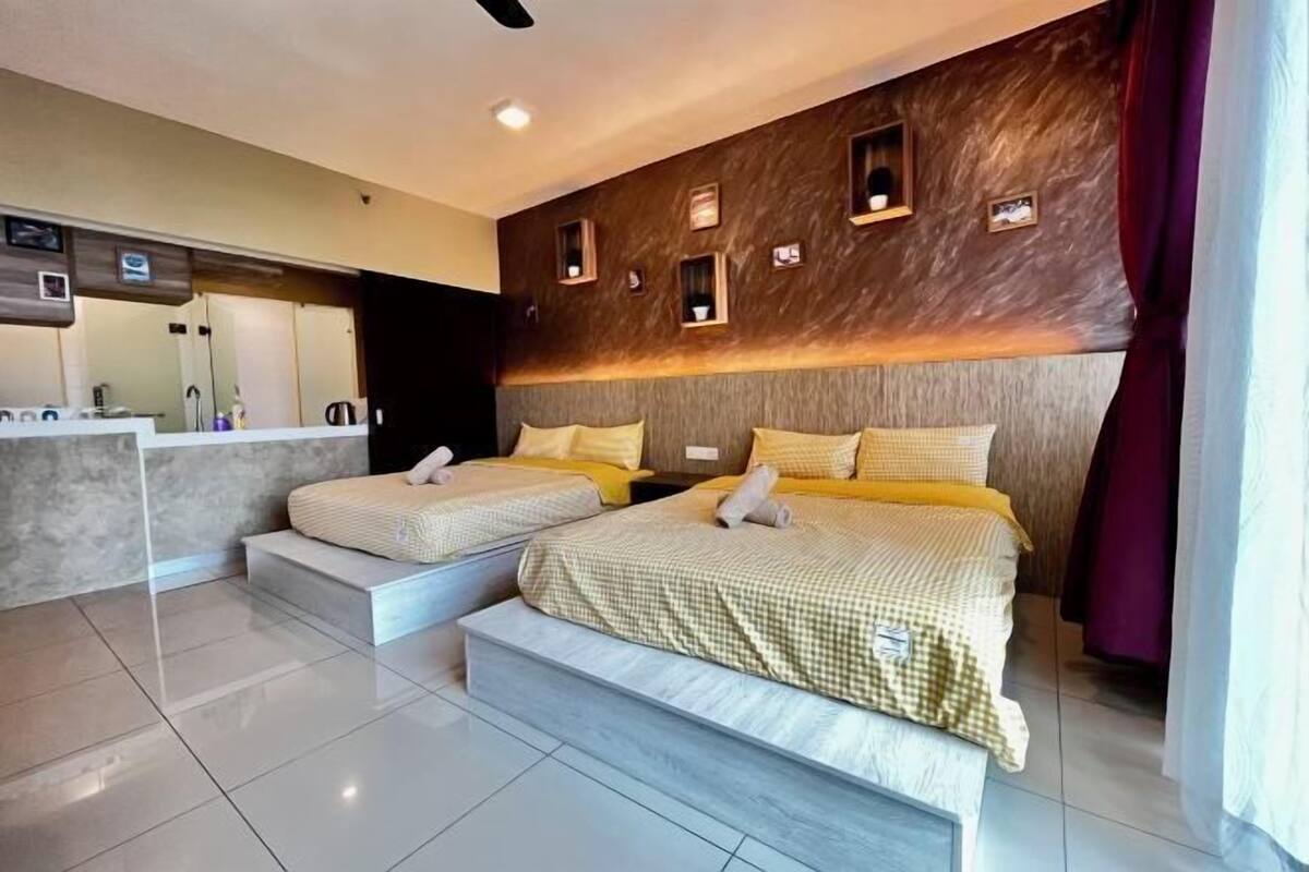 Une chambre d’hôtel moderne avec deux lits, une petite kitchenette et une salle de bain.