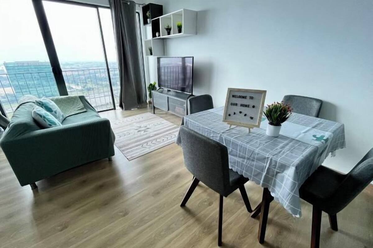 Un salon moderne comprenant un canapé, une table à manger, des chaises, un téléviseur et une vue sur la ville.
