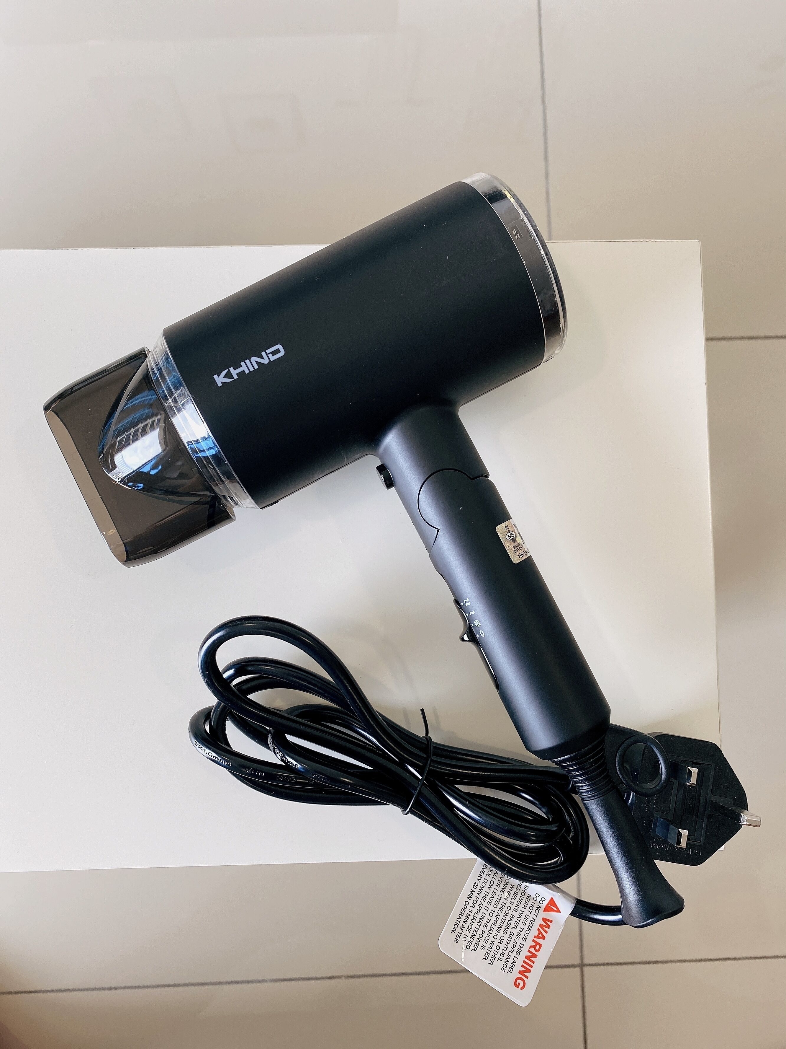 A black hairdryer with a cord and a power adapter.