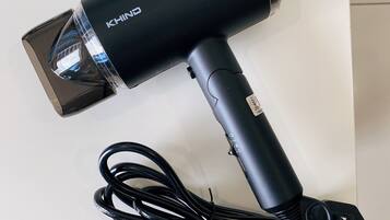 A black hairdryer with a cord and a power adapter.
