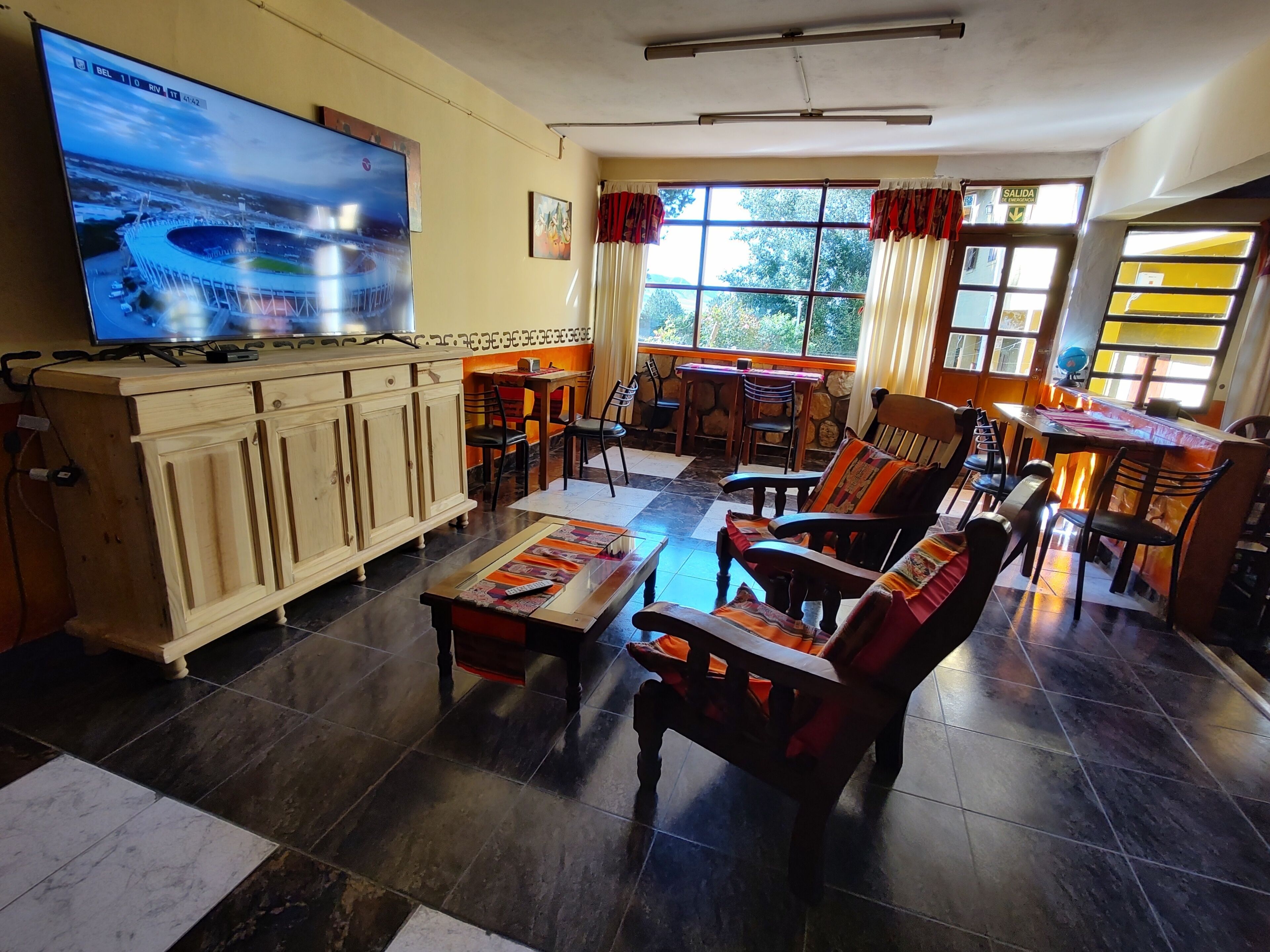 Ein Wohnzimmer mit Fernseher, Holzmöbeln und einem Essbereich mit Tisch und Stühlen.