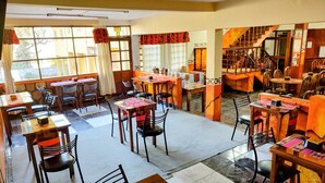 Un restaurante con varias mesas y sillas, una escalera y vistas al exterior.