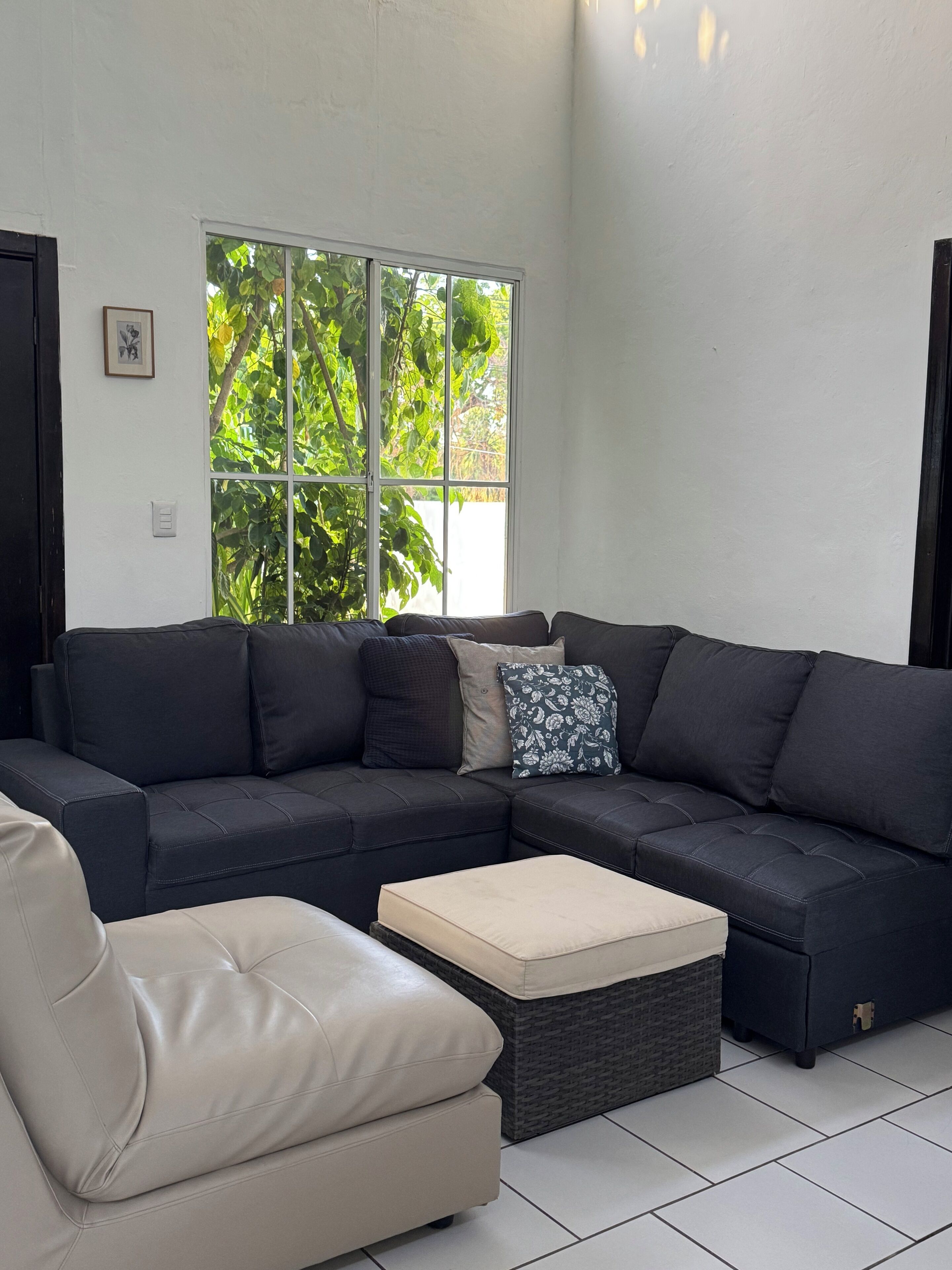 A modern living room with a sectional sofa, a chaise lounge, and a small ottoman.