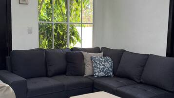 A modern living room with a sectional sofa, a chaise lounge, and a small ottoman.
