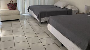 Une chambre avec deux lits, un canapé, une lampe et une fenêtre avec des rideaux.