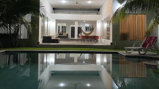 Une maison moderne dotée d’une piscine, d’un hamac et d’un espace repas.