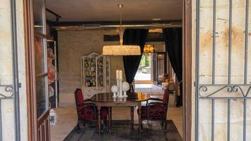 A dining area with a chandelier, a round table, and red upholstered chairs.