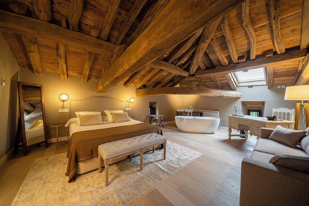 Une chambre spacieuse avec un grand lit, un coin salon, une baignoire et une fenêtre de toit.