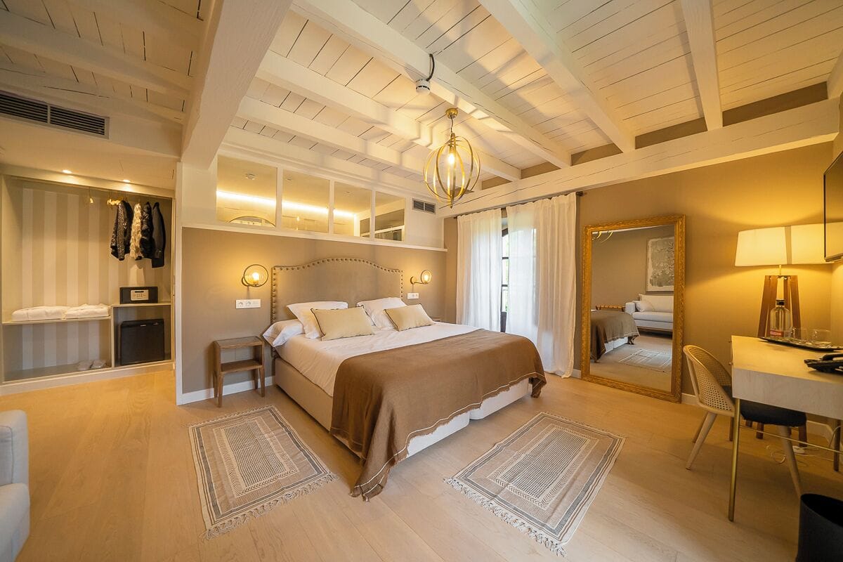 Une chambre à coucher avec un grand lit, des tables de chevet, un bureau et un miroir.