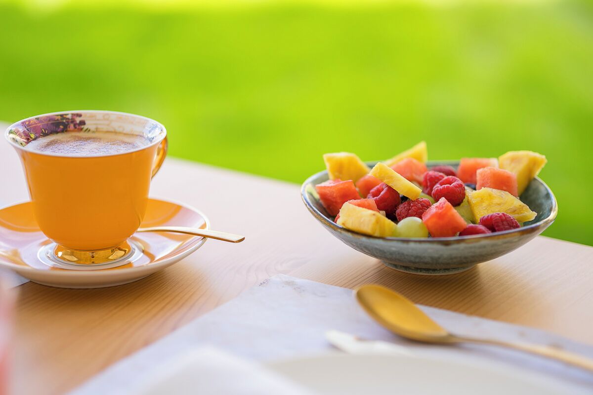 Una taula amb una tassa de cafè i un bol de fruita.